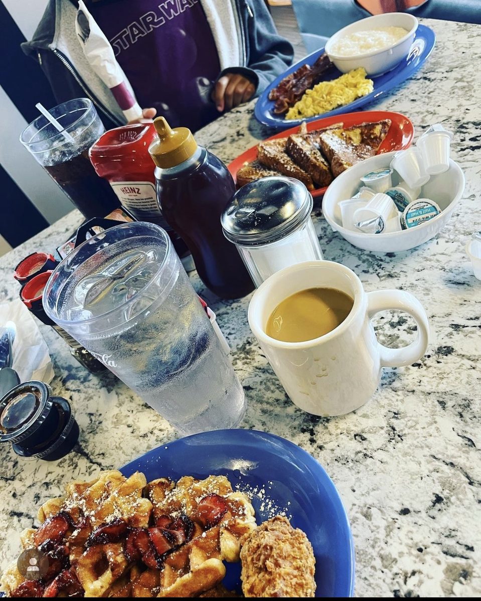 A full Breakfast Club table — waffles with strawberries, fried chicken, french toast, and coffee